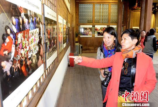 展廳內(nèi)，由臺灣女?dāng)z影家楊欣參展的作品《團圓飯》前，臺灣農(nóng)村美國際觀光發(fā)展協(xié)會理事長、鄧南光影像紀念館館長黃翠文(右)饒有興致地向觀眾講述，該作品的創(chuàng)作經(jīng)過及照片背後的故事。　記者劉可耕 攝